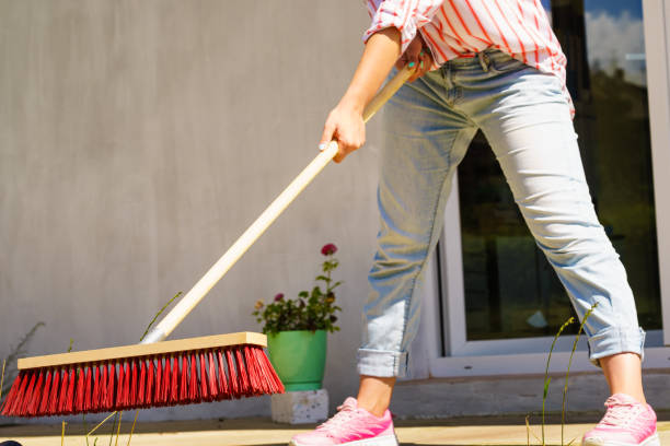 istock Woman using broom to clean up backyard patio 998930054