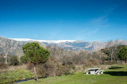 Recreational area next to the Fuentiduena stream on its way through the city of Cerceda, in the province of Madrid, Spain. In the background it can be seen The Guadarrama Mountains