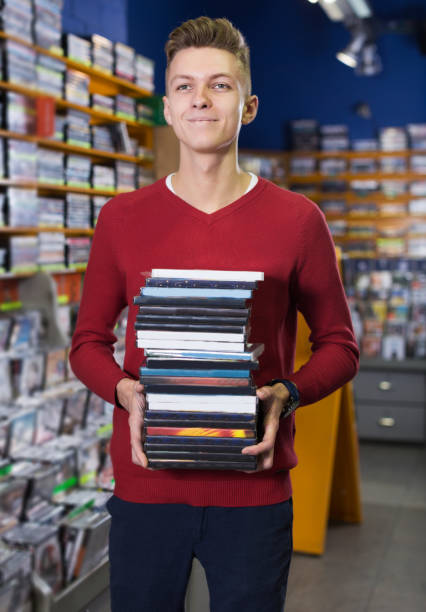 guy holding pile of boxes with dvds - dvd stack cd movie imagens e fotografias de stock