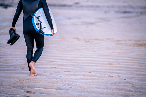 Surfer coming back from sea carrying board