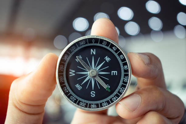 istock holding compass on tree mountain and sea blurry background. Using wallpaper or background travel or navigator image. 998957162