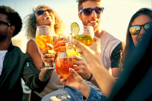 Time spent having fun is time well spent Shot of a group of young friends hanging out and having drinks together outdoors summer party stock pictures, royalty-free photos & images