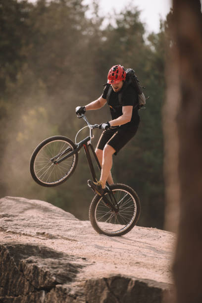 istock handsome trial biker balancing on back wheel on rocks outdoors 998984134