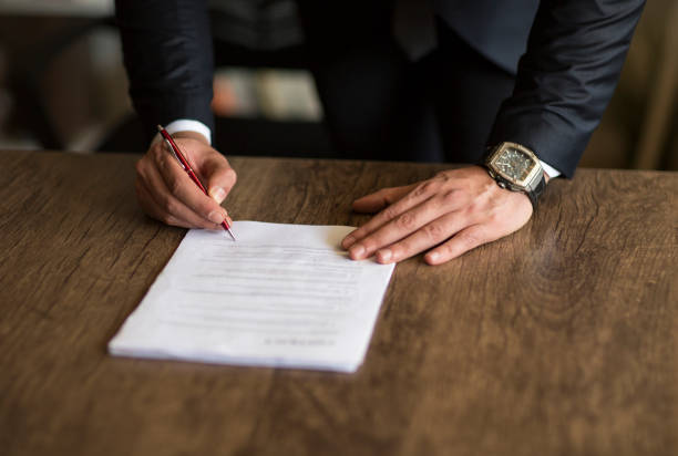 A fountain pen nib hovers over the printed word AGENT on a form, about to sign.