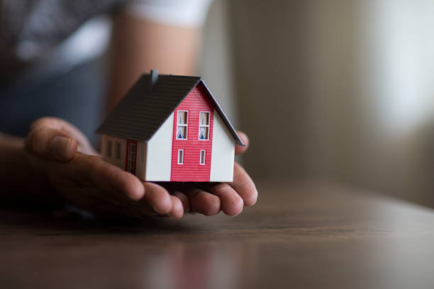 istock Business man hand hold the house model saving small house. 998987440