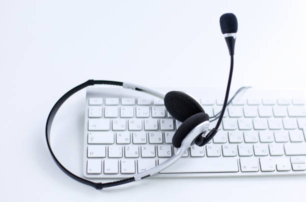 istock Communication support, call center and customer service help desk. VOIP headset on laptop computer keyboard 998990018