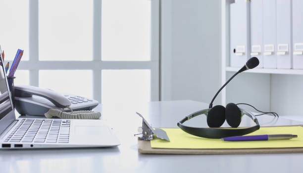 istock Communication support, call center and customer service help desk. VOIP headset on laptop computer keyboard 998996748
