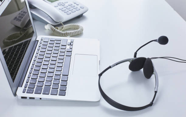 istock Communication support, call center and customer service help desk. VOIP headset on laptop computer keyboard 998996926