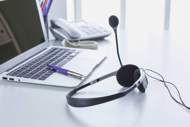 istock Communication support, call center and customer service help desk. VOIP headset on laptop computer keyboard 998996952