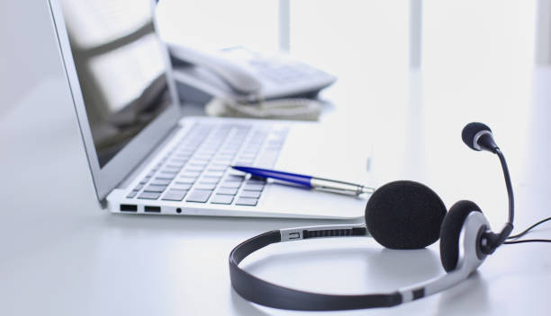 istock Communication support, call center and customer service help desk. VOIP headset on laptop computer keyboard 998996996