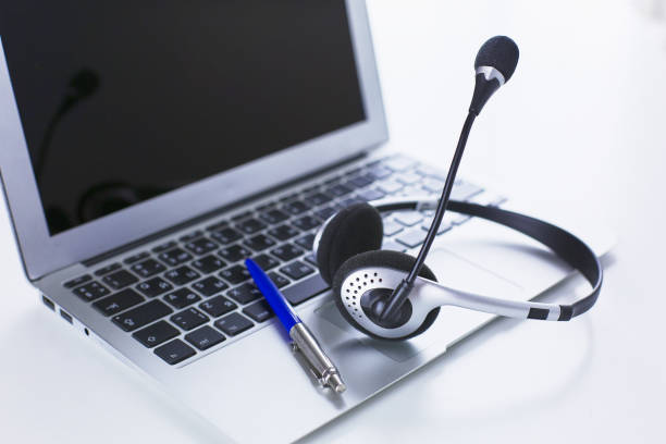 istock Communication support, call center and customer service help desk. VOIP headset on laptop computer keyboard 998997174