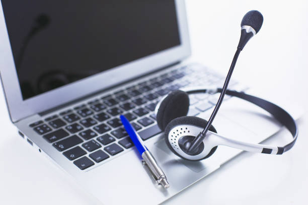 istock Communication support, call center and customer service help desk. VOIP headset on laptop computer keyboard 998997218