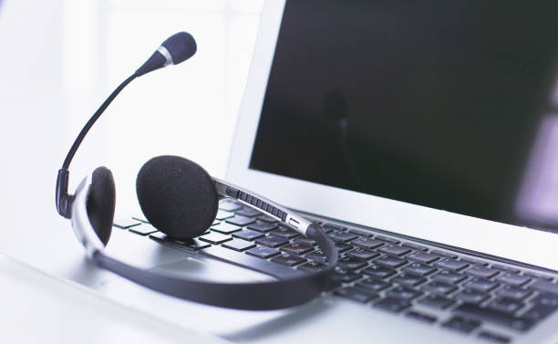 istock Communication support, call center and customer service help desk. VOIP headset on laptop computer keyboard 999001160