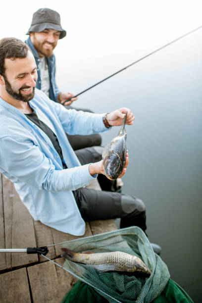 istock Fishermen with fish on the lake 999001346