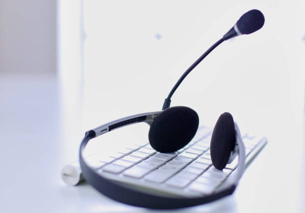 istock Communication support, call center and customer service help desk. VOIP headset on laptop computer keyboard 999001438