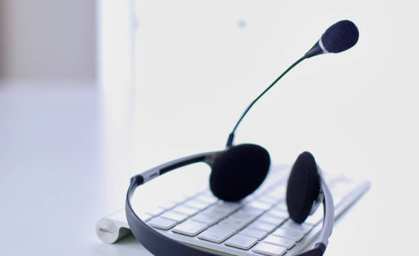 istock Communication support, call center and customer service help desk. VOIP headset on laptop computer keyboard 999001464