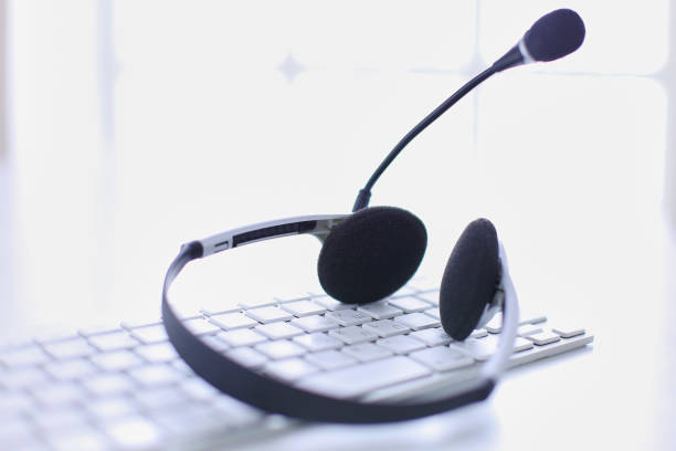 istock Communication support, call center and customer service help desk. VOIP headset on laptop computer keyboard 999001478