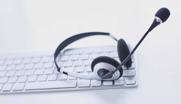 istock Communication support, call center and customer service help desk. VOIP headset on laptop computer keyboard 999001736