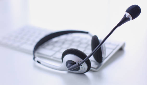 istock Communication support, call center and customer service help desk. VOIP headset on laptop computer keyboard 999004098
