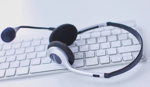 istock Communication support, call center and customer service help desk. VOIP headset on laptop computer keyboard 999004452