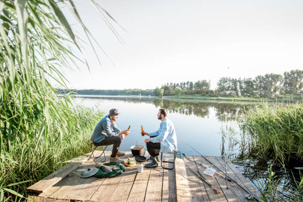 istock Men relaxing with beer while fishing on the lake 999004508