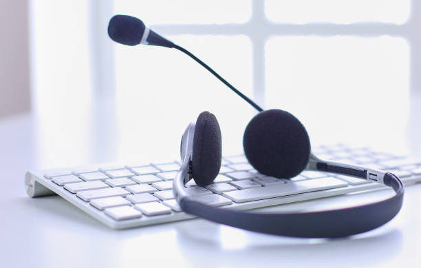 istock Communication support, call center and customer service help desk. VOIP headset on laptop computer keyboard 999005050