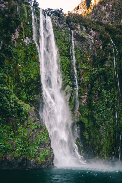 istock Flowing water fall into lake with green moss and leaves 999021792