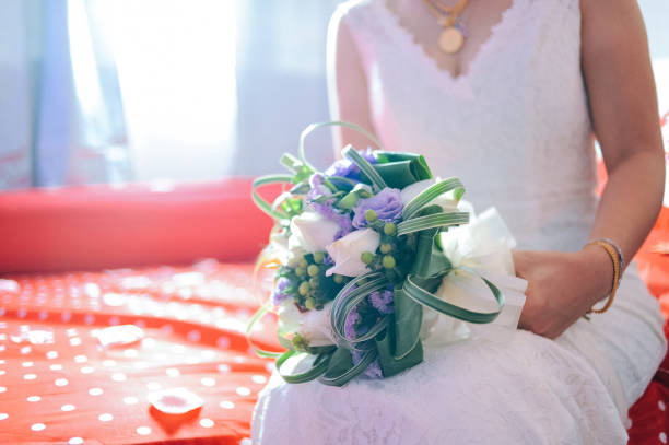 istock Bride holding beautiful bouquet while sitting on bed at home 999030684