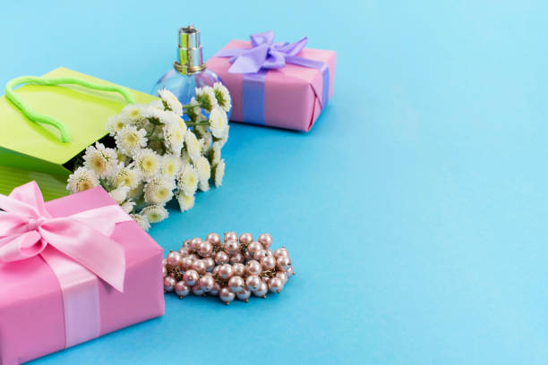dekoracyjne pudełka kompozycji z prezentami kwiaty biżuteria damska zakupy wakacje niebieskie tło. - pink perfume bracelet necklace zdjęcia i obrazy z banku zdjęć