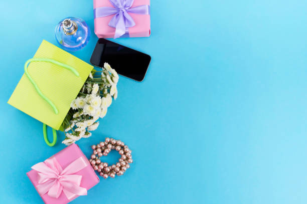 dekorative komposition boxen mit geschenke blumen frauen schmuck shopping urlaub blauen hintergrund. - pink perfume bracelet necklace stock-fotos und bilder