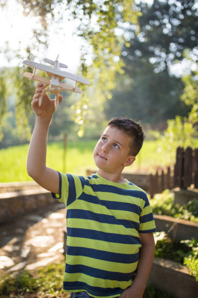 istock Boy playing with toy airplane outdoors in summer 999051370