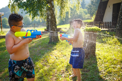 Little boys playing with water guns in summer