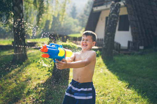 Little boy splashing with water gun