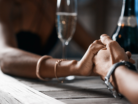 Cropped shot of a man and woman compassionately holding hands at a table