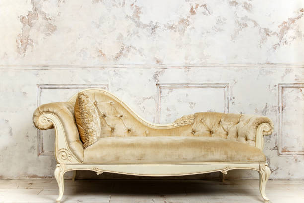 istock Luxurious golden sofa on a background of old white wall 999080298