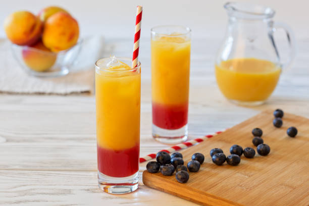 ice cold peach juice with grenadine syrup on rustic wooden table. selective focus - tea berry currant fruit imagens e fotografias de stock