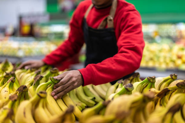 istock Supermarket Employee Choosing Bananas 999087414