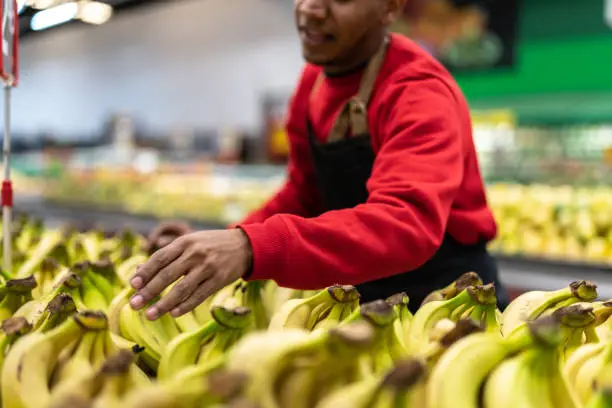 Photo of Supermarket Employee Choosing Bananas