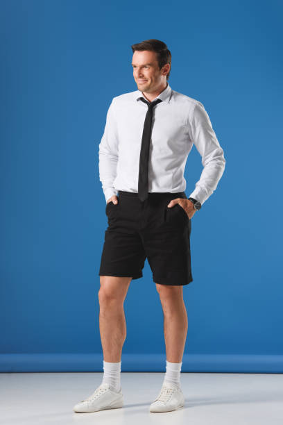 istock smiling stylish man in shorts with hands in pockets on blue background 999094114