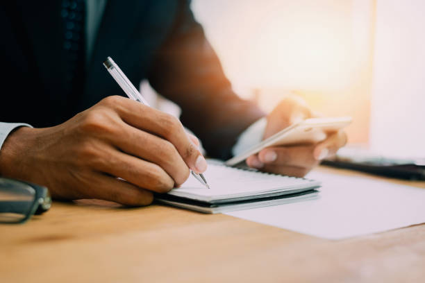 istock Checklist Writing Notice Remember Planning Concept,home office desk background,hand holding pen and writing note on wood table. 999094474