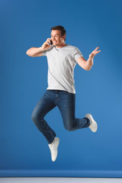 istock happy man talking by smartphone and jumping on blue 999096888