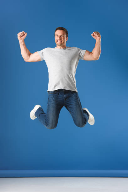 istock excited man jumping and triumphing on blue 999096908