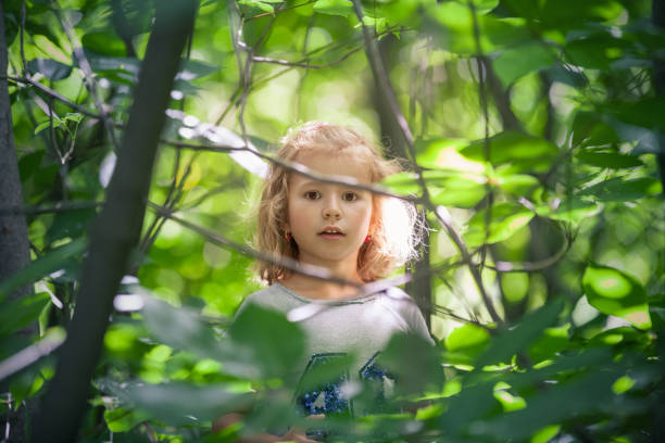 istock Cute little girl hiding in forest 999097656