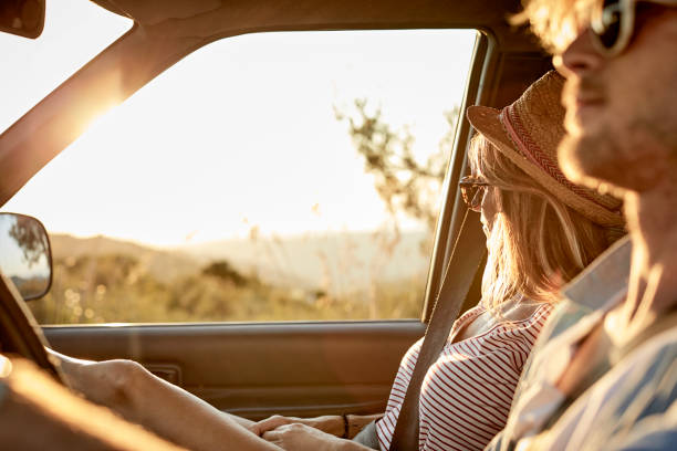 Woman sitting by man driving van during road trip