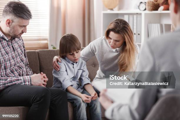 Mother Hugging Her Autistic Son Sitting Next To A Father During A Family Therapy Stock Photo - Download Image Now