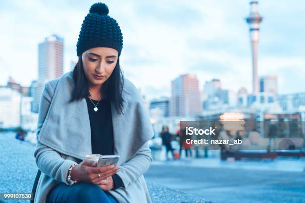 Checking Social Media On Phone With Auckland City In Background Stock Photo - Download Image Now