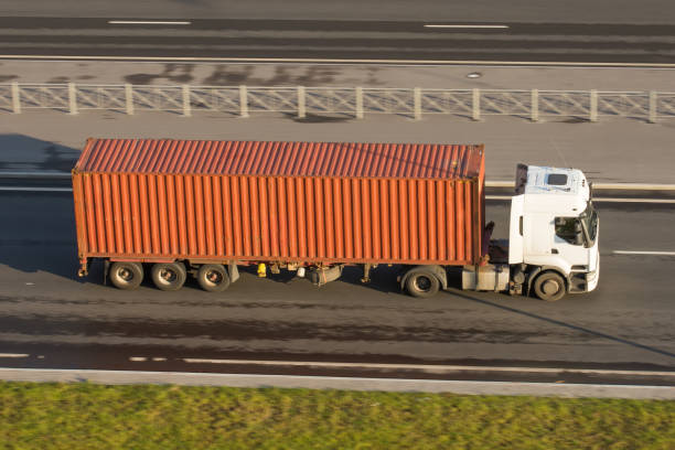 istock Large truck with container trailer on the highway asphalt, evening sunset light. View from above. 999111634