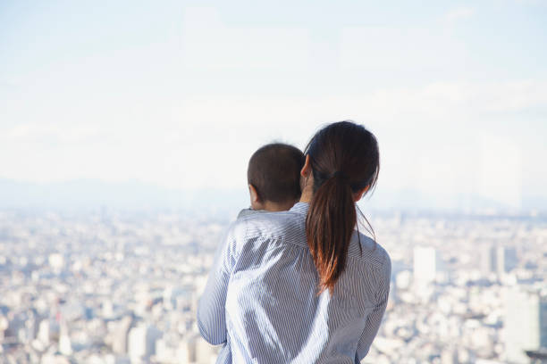 母と息子の高層ビルから街の景色を見て - child looking blank offspring ストックフォトと画像