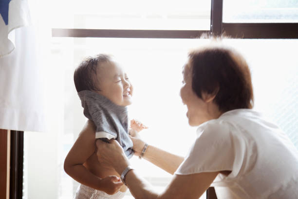 istock Grandmother helping her grandson change his clothes 999115448