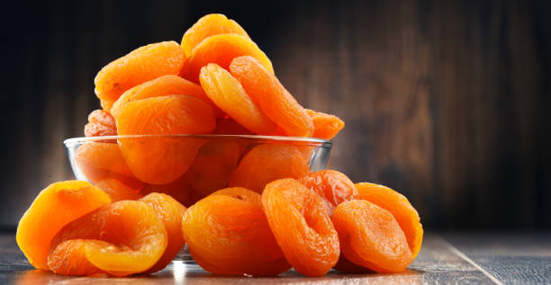 schale mit getrockneten aprikosen auf holztisch - dried apricot stock-fotos und bilder